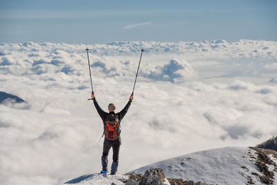 Man standing on snowcapped mountain against sky