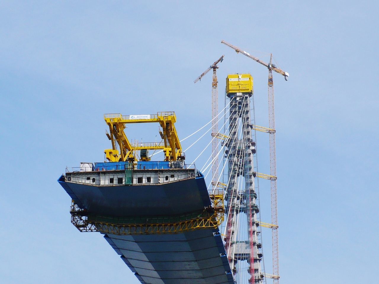 LOW ANGLE VIEW OF CRANE BY PIER AGAINST SKY