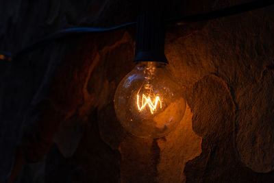 Low angle view of illuminated light bulb hanging from ceiling