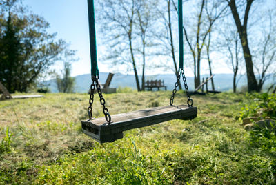 Empty swing on field against sky