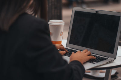 Midsection of woman using laptop on table