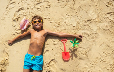 Portrait of young man standing on sand at beach