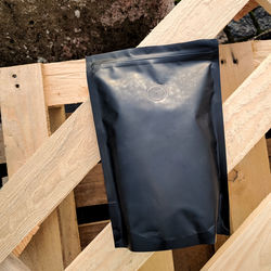 Black unbranded bag of coffee on wooden planks