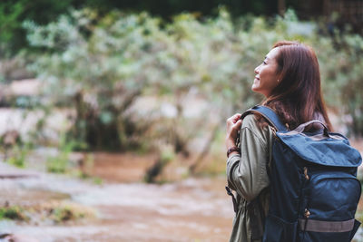 A female traveler with backpack walking by mountain stream for hiking concept