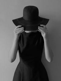 Woman wearing hat while standing against wall