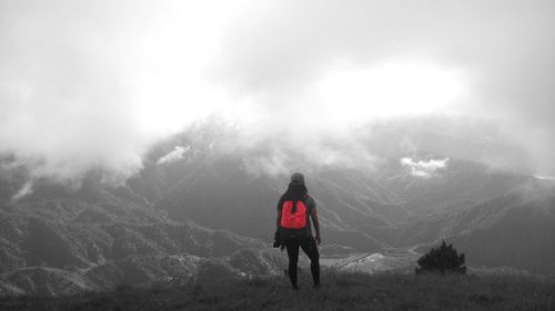 Rear view of man standing on mountain against sky