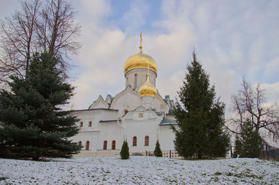 Church by trees against sky during winter