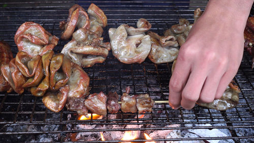 Close-up of man preparing food on barbecue grill