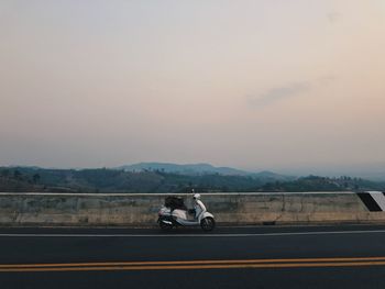 Cars on road against sky during sunset