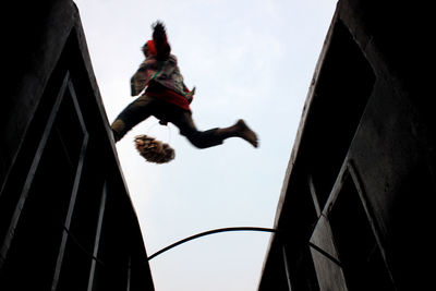 Low angle view of vendor jumping on train against clear sky