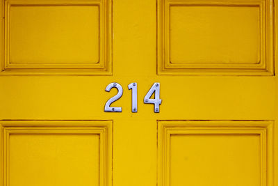House number 214 on a yellow wooden front door in london