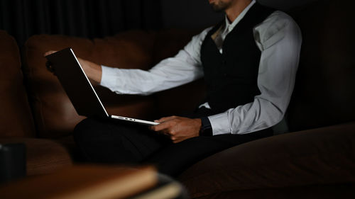 Midsection of businessman using laptop at office