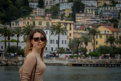 Woman wearing sunglasses standing against buildings