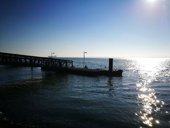Silhouette pier over sea against clear sky