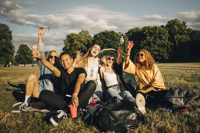 Happy young friends enjoying while sitting on grass at music concert