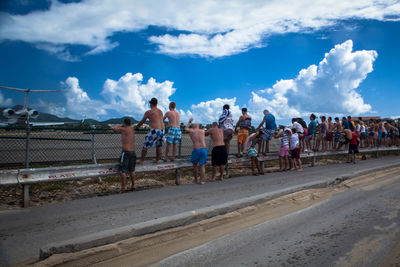 People on road against cloudy sky