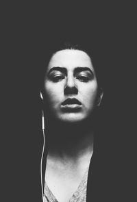 Close-up portrait of young woman against black background