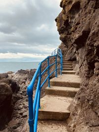 Staircase leading towards sea against sky