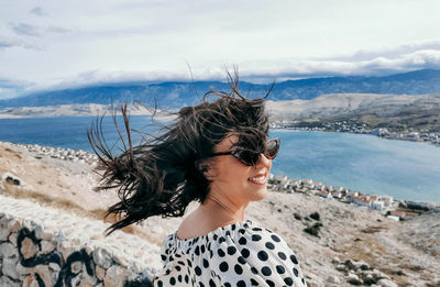 Young woman wearing sunglasses on beach against sky