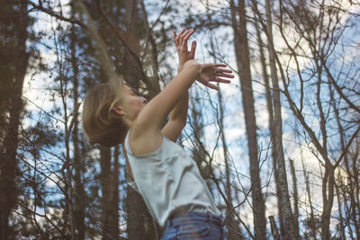 Low angle view of child on tree in forest