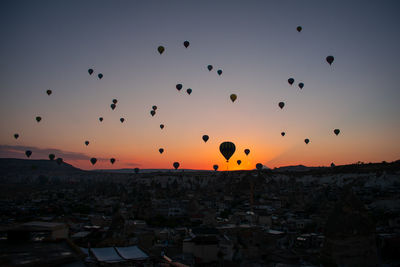 Silhouette of hot air balloons against sky during sunset