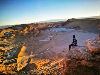 Man sitting on rock formation at valle de la luna