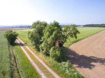 Road amidst field against clear sky