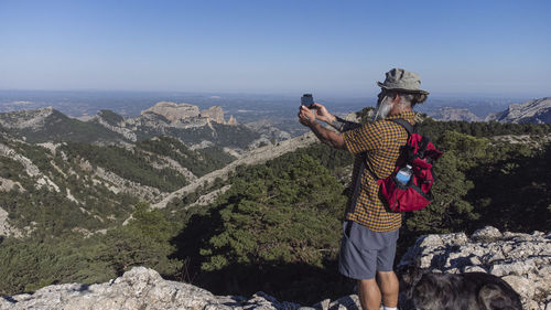 Hiker taking photos of beautiful mountain landscape with mobile phone person