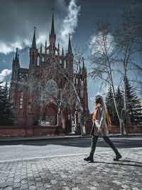 Full length of woman walking against building in city