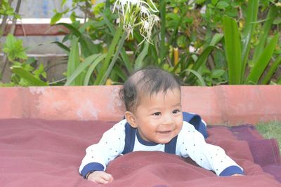 Smiling baby boy looking away while lying on blanket