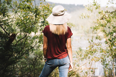 Rear view of woman standing by plants and lake