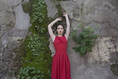 Portrait of young woman standing by wall