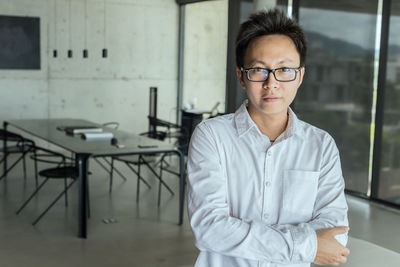 Portrait of businessman wearing eyeglasses while standing in office