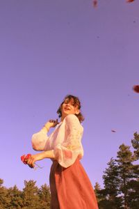 Low angle view of woman standing against clear sky