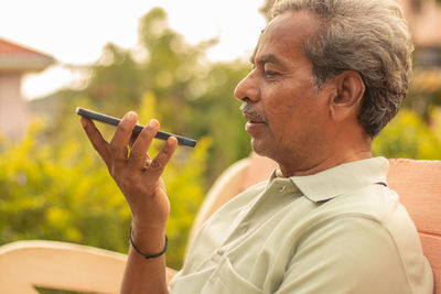 Man holding smart phone on bench