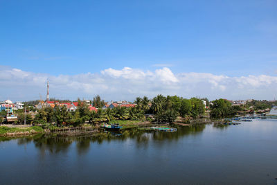 Scenic view of river by buildings against sky