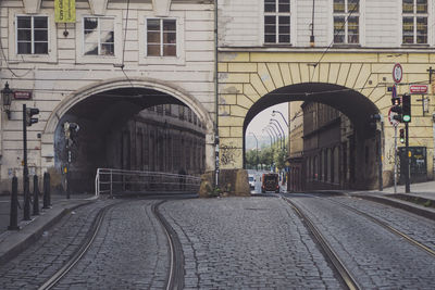 Railroad tracks on street passing through arches in buildings