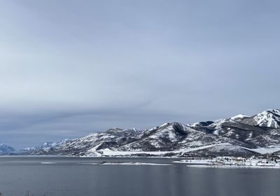 Scenic view of snowcapped mountains by sea against sky