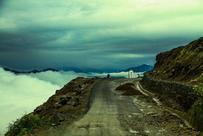 Empty road leading towards mountain against sky
