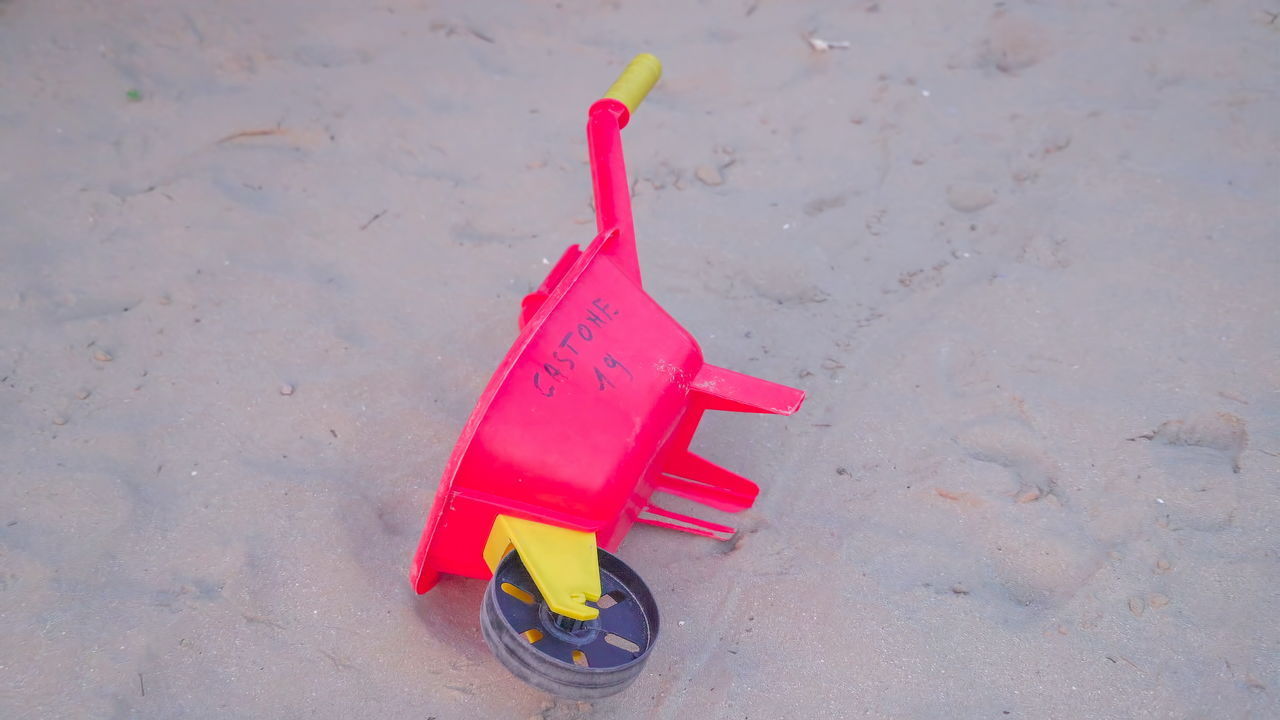 HIGH ANGLE VIEW OF PLASTIC TOY ON BEACH