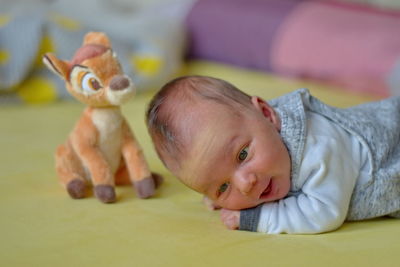 Portrait of cute baby girl lying on toy