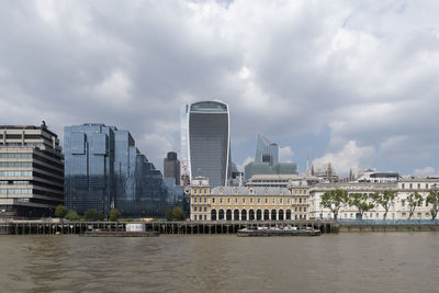 Buildings by river against sky in city