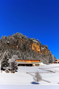 Snow covered landscape against clear blue sky