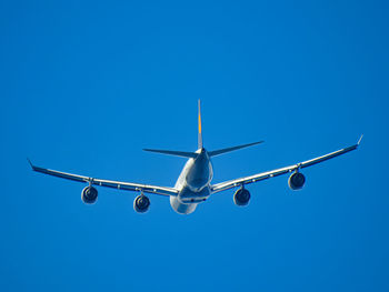 Low angle view of airplane flying against blue sky