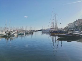 Sailboats moored at harbor against blue sky