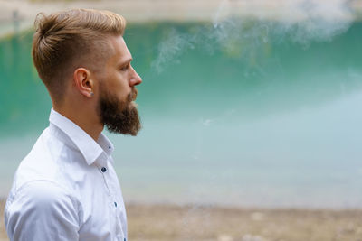Young man beard smokes cigarette or tobacco. guy is addicted to cigarettes