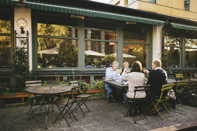 Happy senior couples toasting champagne flutes at outdoor restaurant