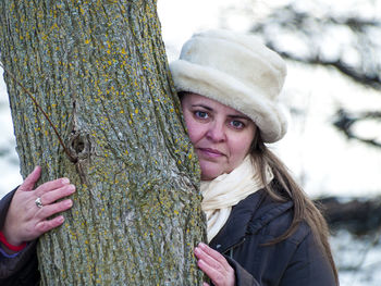 Portrait of woman embracing tree trunk