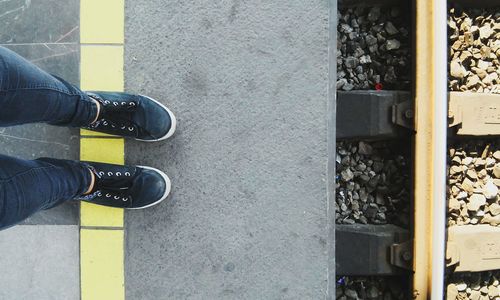 Low section of person standing at railroad station platform