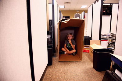 Portrait of boy sitting in cardboard box at office